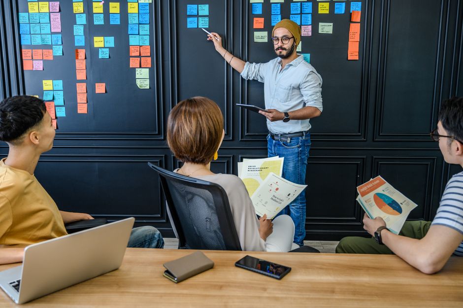 Diverse team collaborating in a modern office environment with sticky notes and charts.